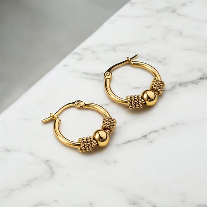 Gold hoop earrings on a marble surface